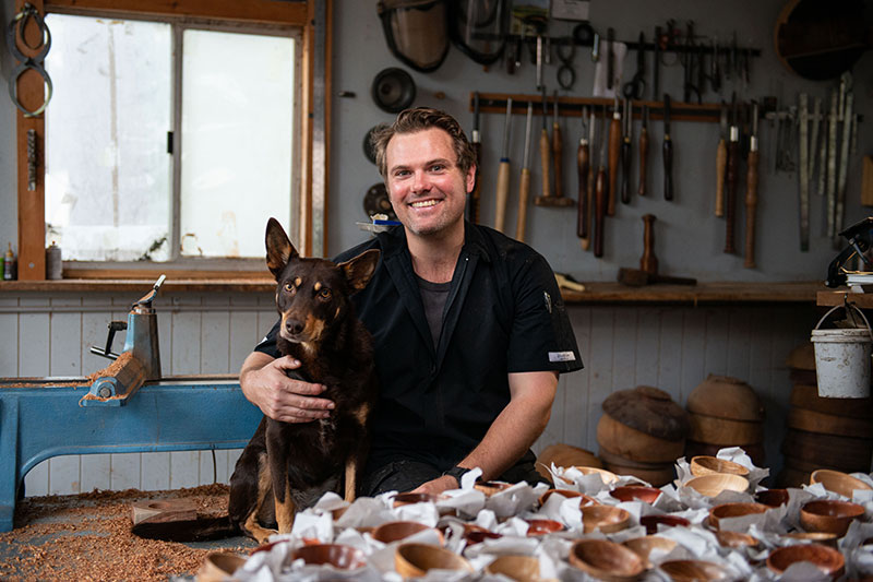 Army veteran Kerry Corney sitting with his dog in his workshop. 
