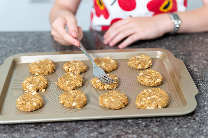 ANZAC biscuits on a baking tray being prepped for the oven.  
